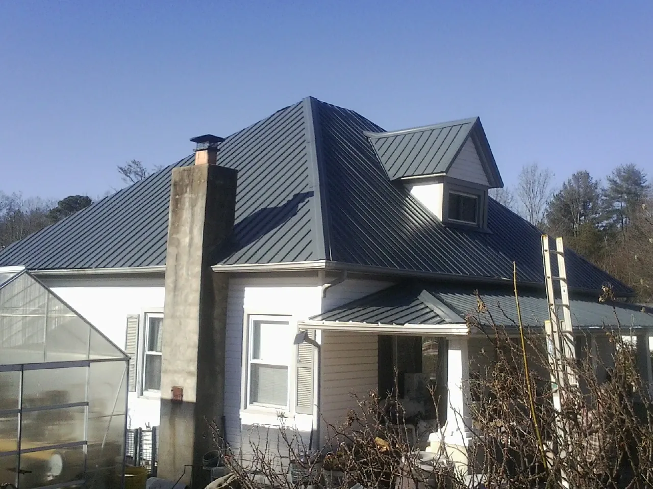 Dark blue standing seam metal roof on a white farmhouse with dormer — Slate & Tile Roof Repair by Roofing Brothers in Moss Beach