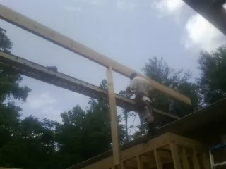 Carpenter setting a ridge beam over a new addition frame — Ice Dam Removal by Roofing Brothers in Moss Beach