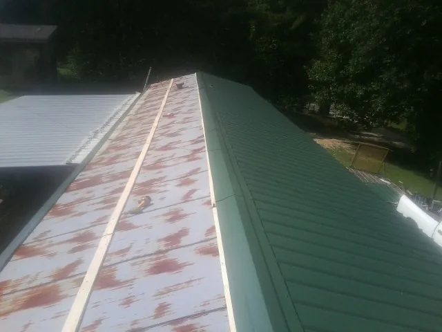 Old rusted panels beside newly installed green metal roofing — Wind Damage Roof Repair by Roofing Brothers in Moss Beach