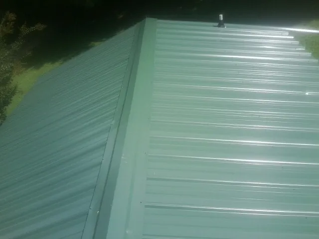 New green metal panels meeting at the ridge of a roof — Flat Roof Repair work by our crew in Moss Beach
