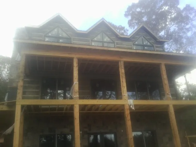 Dormers and porch framing on a large log home under construction — Roof Coating work by our crew in Moss Beach