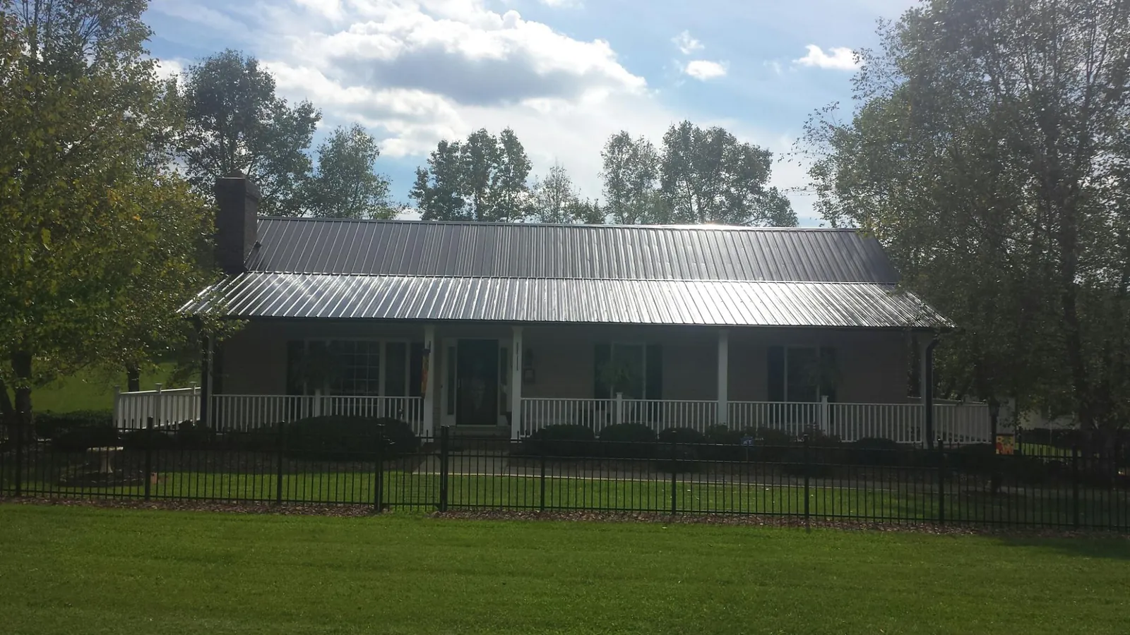 Gray metal roof on a brick ranch with a full width front porch — Gutter Guard Installation work by our crew in Moss Beach