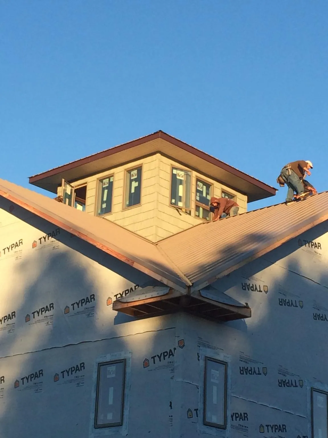 Roofers working around a rooftop cupola on a new metal roof at sunset — Roof Waterproofing in Moss Beach by Roofing Brothers